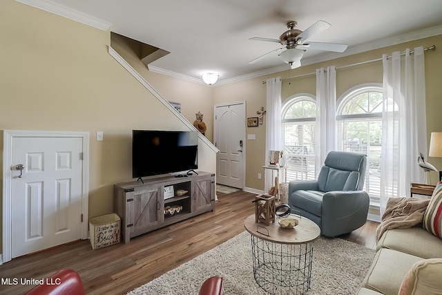 living area with ceiling fan, baseboards, crown molding, and light wood-style flooring