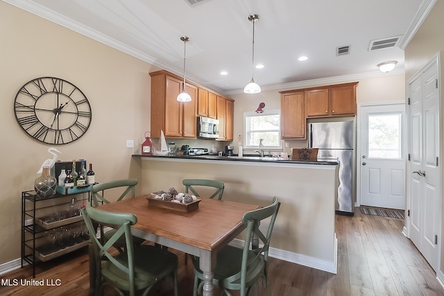 kitchen featuring dark countertops, ornamental molding, stainless steel appliances, and visible vents