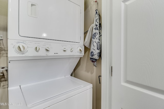 clothes washing area featuring stacked washer / dryer and laundry area