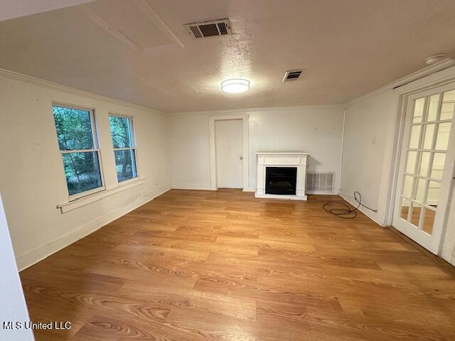 153 Saint Peter St, Biloxi, MS 39530 - unfurnished living room featuring a fireplace with raised hearth, light wood-type flooring, ornamental molding, and baseboards