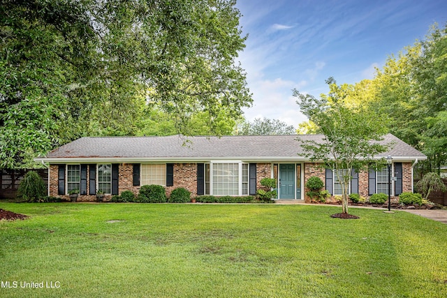 ranch-style home with brick siding, a front lawn, and roof with shingles