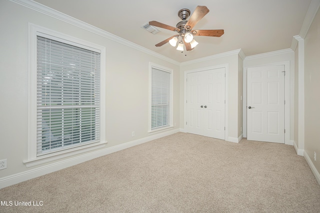 unfurnished bedroom featuring ornamental molding, carpet, baseboards, a closet, and a ceiling fan