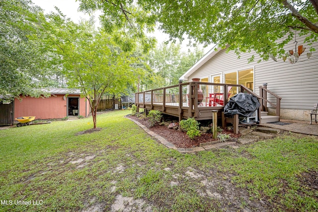 view of green lawn featuring a deck and an outbuilding