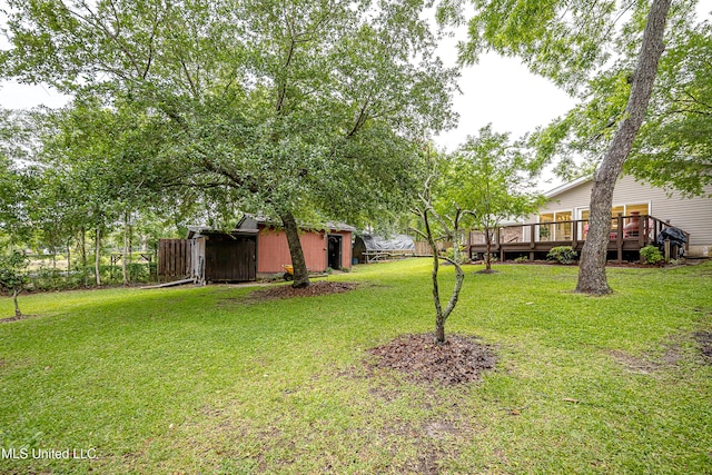view of grassy yard with a deck, an outbuilding, and a shed