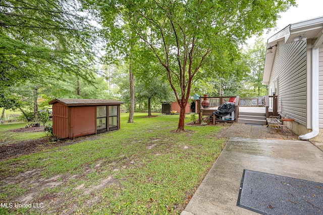 view of green lawn featuring a storage shed, a deck, and an outbuilding