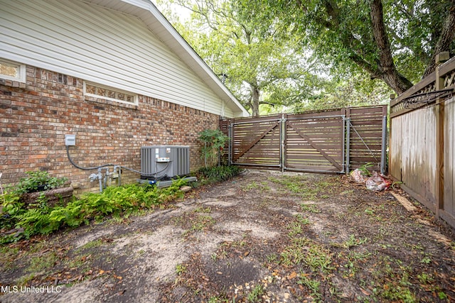 view of yard featuring a gate, central AC unit, and fence