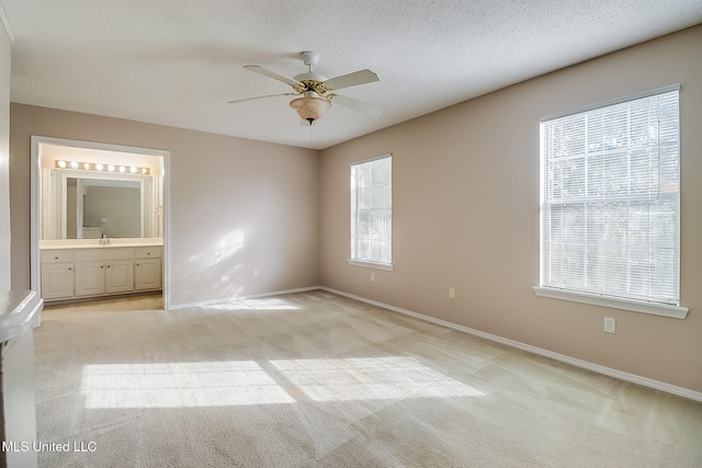 unfurnished bedroom with connected bathroom, light colored carpet, ceiling fan, and sink