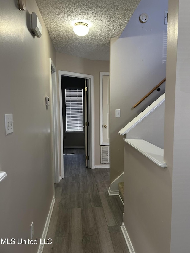 hallway with dark hardwood / wood-style flooring and a textured ceiling