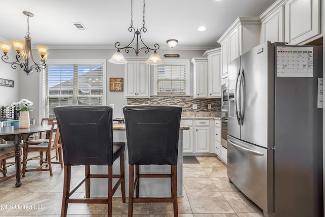 3841 Chateau Cv, Ocean Springs, MS 39564 - kitchen featuring appliances with stainless steel finishes, crown molding, plenty of natural light, white cabinets, and a chandelier