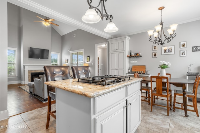 3841 Chateau Cv, Ocean Springs, MS 39564 - kitchen with stainless steel gas cooktop, white cabinets, ornamental molding, vaulted ceiling, and decorative light fixtures