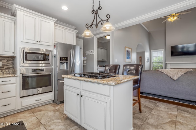 3841 Chateau Cv, Ocean Springs, MS 39564 - kitchen featuring stainless steel appliances, open floor plan, arched walkways, ornamental molding, and white cabinets