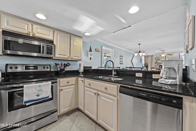 kitchen featuring ceiling fan with notable chandelier, sink, dark stone countertops, light tile patterned floors, and appliances with stainless steel finishes