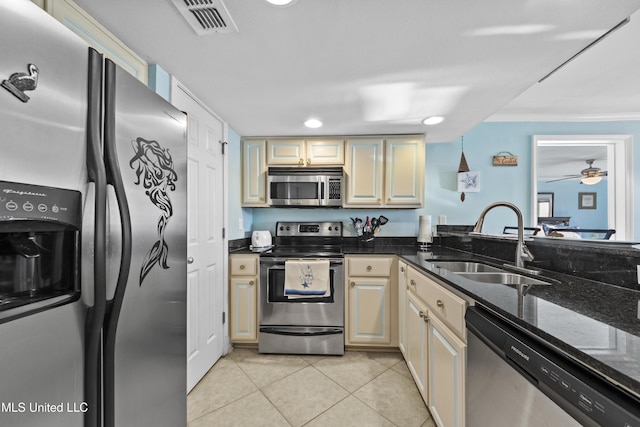 kitchen featuring ceiling fan, sink, dark stone counters, light tile patterned floors, and appliances with stainless steel finishes