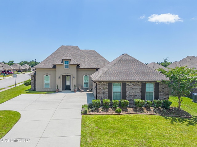3936 David Ln, Diberville, MS 39540 - french country inspired facade featuring a front lawn, stucco siding, central AC, roof with shingles, and brick siding