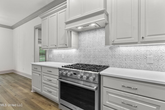 kitchen with white cabinets, backsplash, stainless steel stove, custom range hood, and dark wood-type flooring