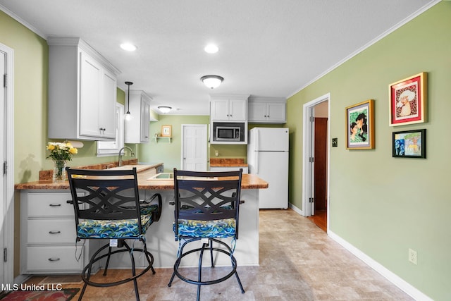 530 Oakhurst Dr, Hernando, MS 38632 - kitchen featuring freestanding refrigerator, stainless steel microwave, a peninsula, white cabinets, and ornamental molding