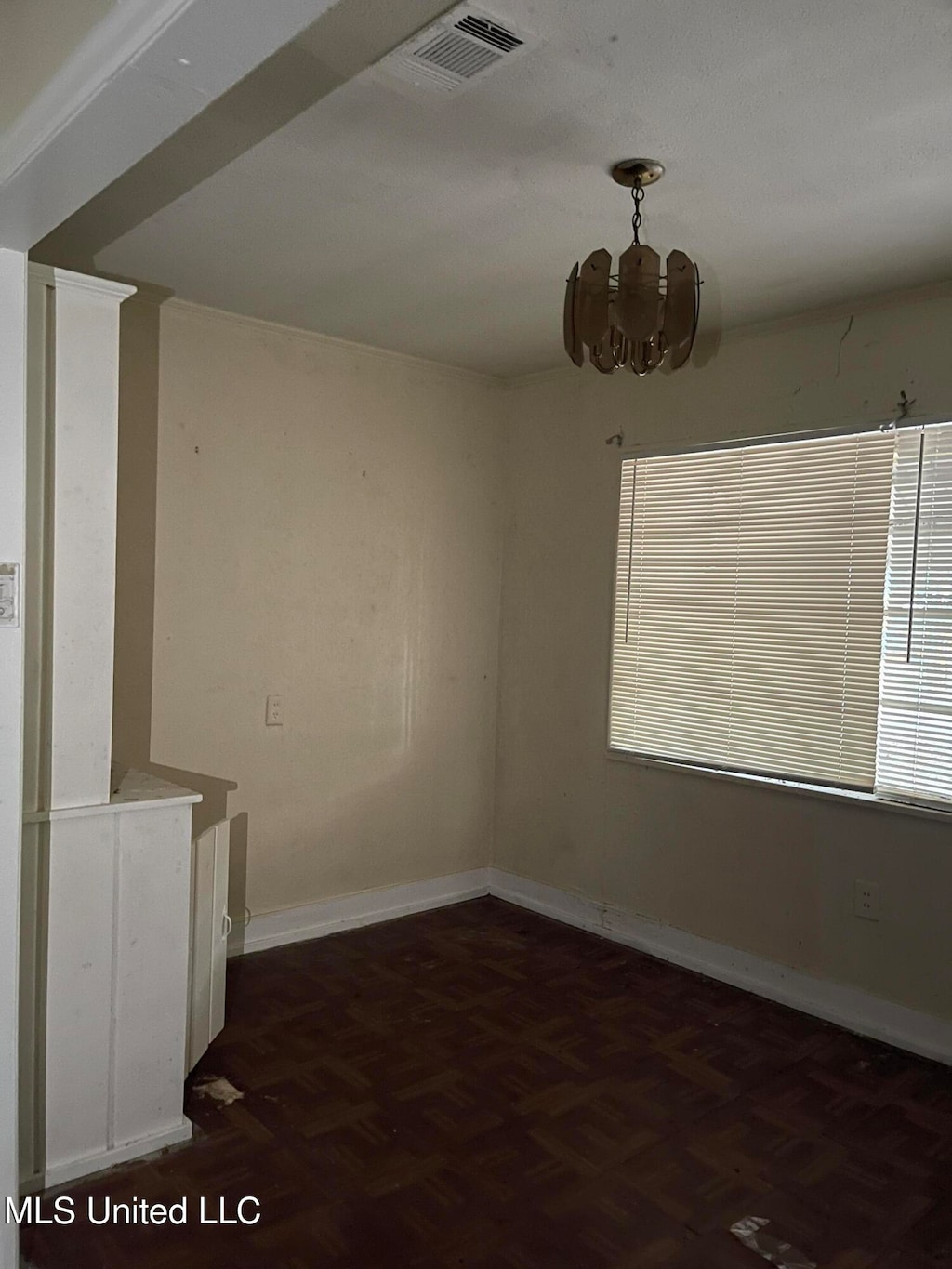 spare room featuring dark parquet flooring and a notable chandelier