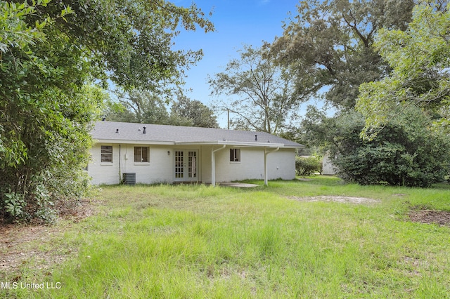 rear view of property featuring central AC and a lawn