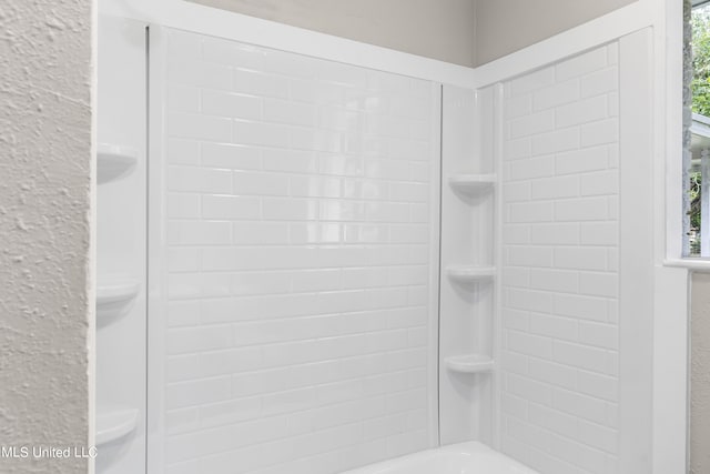 bathroom featuring toilet and tiled shower / bath