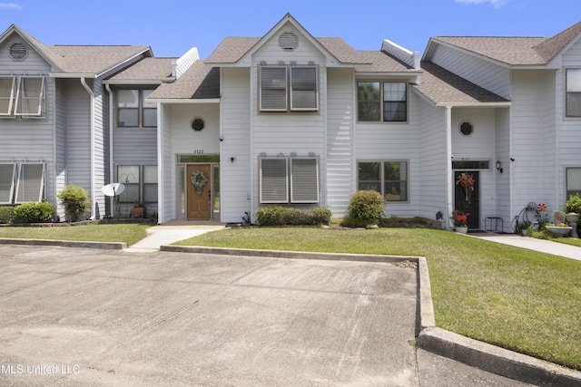 multi unit property with a shingled roof and a front lawn