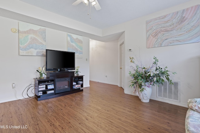 living room with visible vents, a ceiling fan, baseboards, and wood finished floors