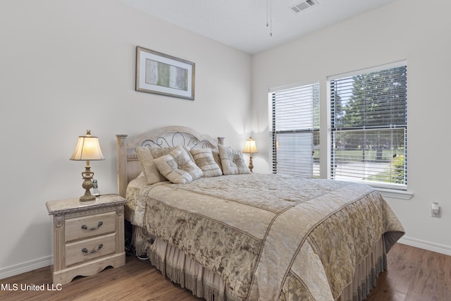 bedroom featuring baseboards, visible vents, and wood finished floors