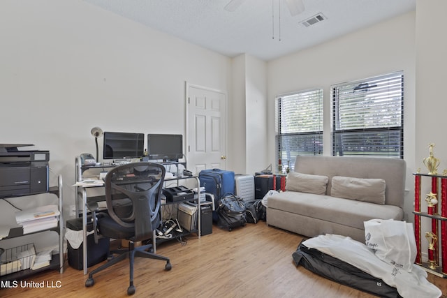 office space featuring a ceiling fan, wood finished floors, and visible vents