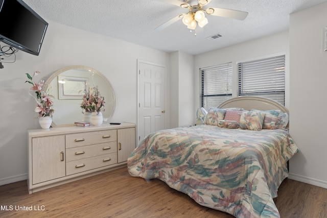 bedroom featuring ceiling fan, light wood finished floors, a textured ceiling, baseboards, and visible vents