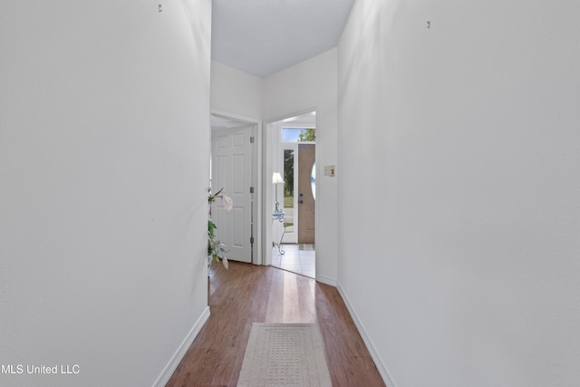 corridor with baseboards and wood finished floors