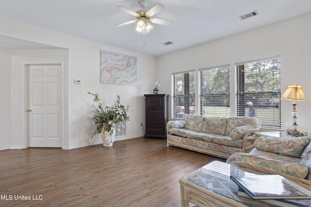 living room with baseboards, ceiling fan, wood finished floors, and visible vents
