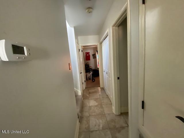 hallway with light tile patterned flooring and baseboards