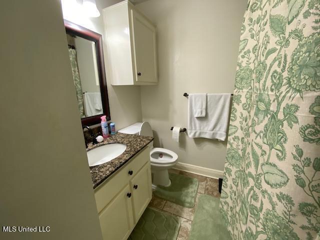 bathroom with a shower with shower curtain, toilet, vanity, and baseboards