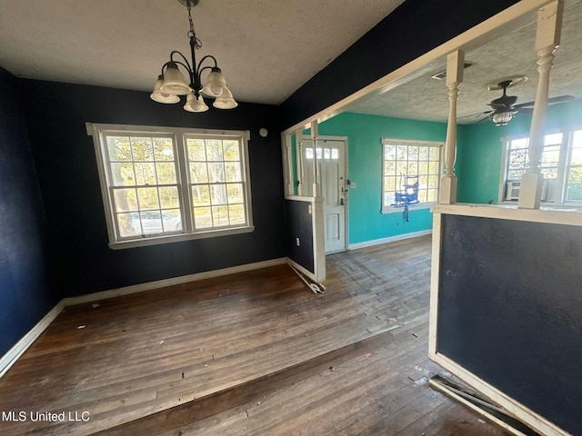 unfurnished dining area featuring wood-type flooring, ceiling fan with notable chandelier, and a textured ceiling