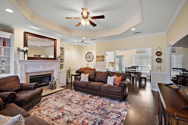 205 Stonebriar Ln, Brandon, MS 39042 - living area with a tray ceiling, a ceiling fan, ornamental molding, dark wood-style flooring, and a tile fireplace