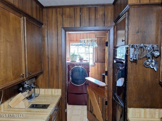 laundry room featuring wood walls, washer / clothes dryer, and a notable chandelier