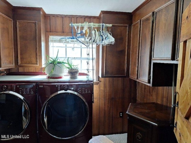 washroom featuring cabinets, wooden walls, and washing machine and clothes dryer