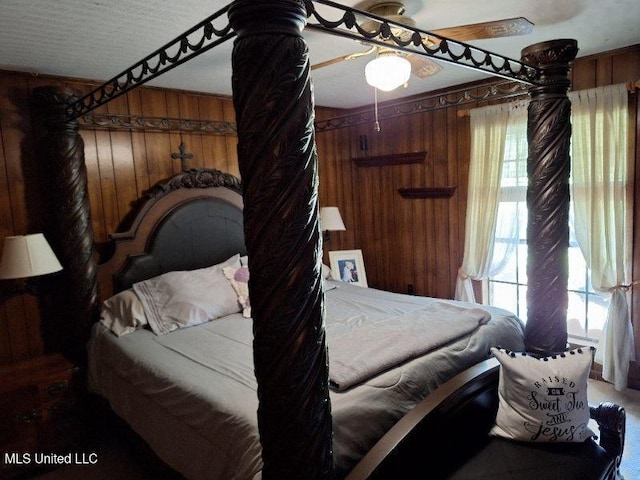 bedroom with ceiling fan and wood walls