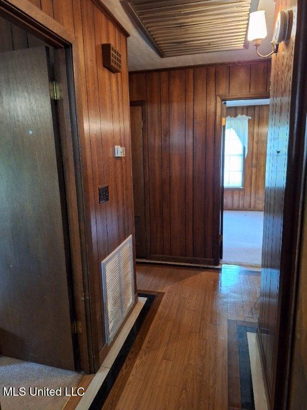 hallway featuring wood-type flooring and wood walls