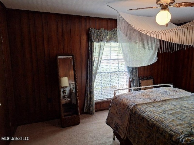 bedroom with wooden walls, light colored carpet, and ceiling fan