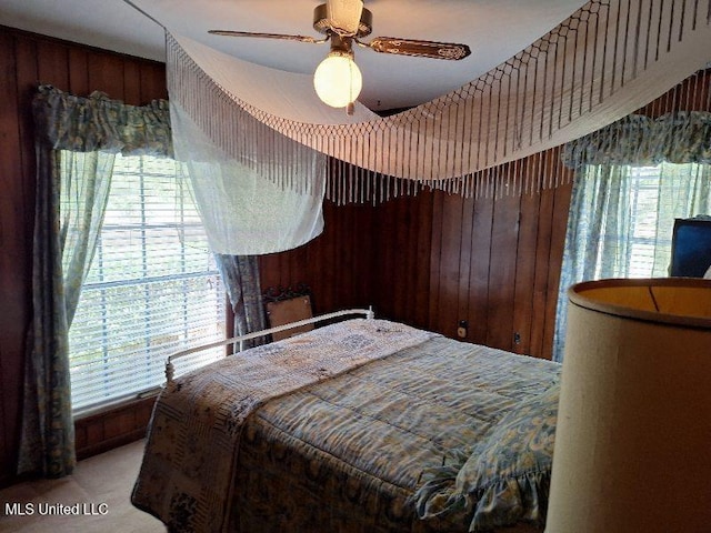 bedroom featuring ceiling fan and wooden walls