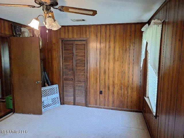 unfurnished bedroom with a closet, ceiling fan, and wood walls