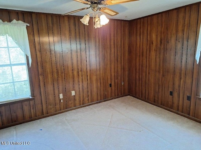 unfurnished room featuring ceiling fan, plenty of natural light, and wooden walls