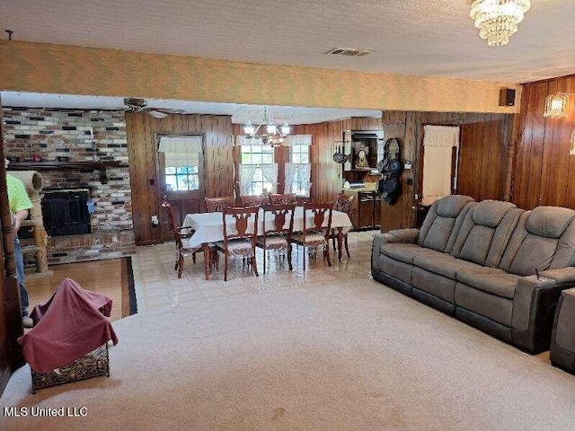 carpeted living room featuring wood walls, a textured ceiling, and ceiling fan with notable chandelier