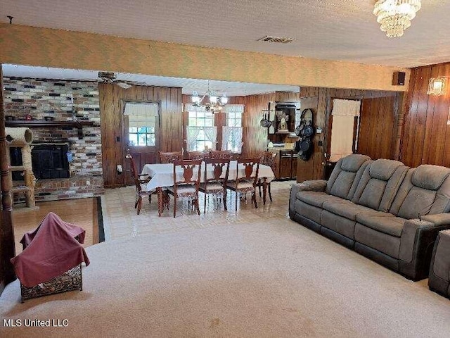 carpeted living room with a textured ceiling, an inviting chandelier, and wood walls