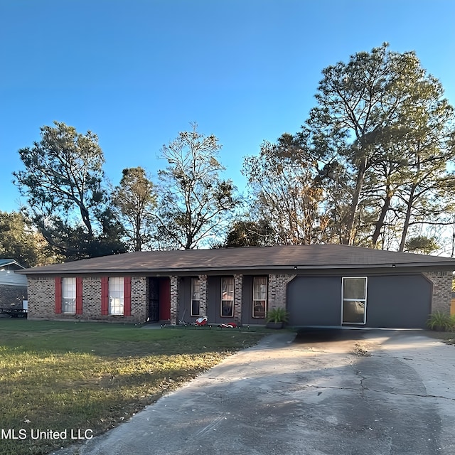 ranch-style home featuring a garage, driveway, brick siding, and a front lawn