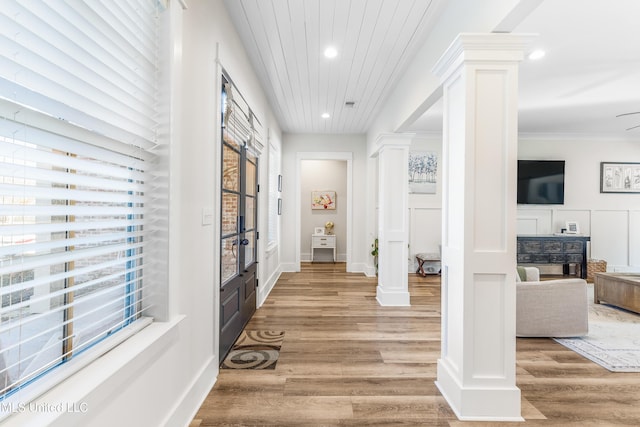 corridor with decorative columns, crown molding, and light hardwood / wood-style flooring