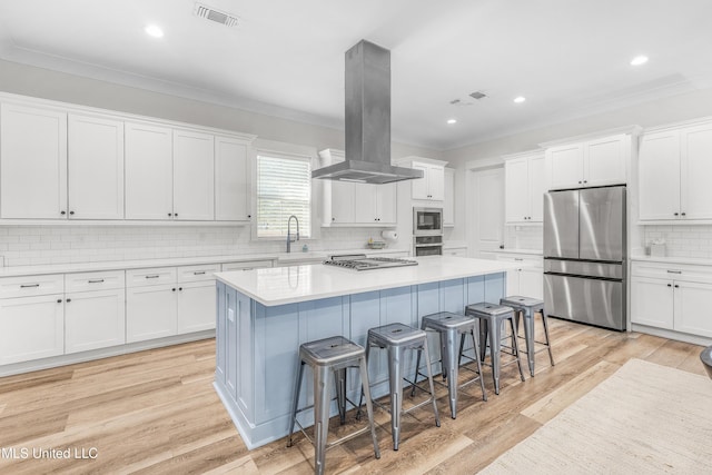 kitchen with island exhaust hood, appliances with stainless steel finishes, a kitchen bar, a center island, and white cabinetry