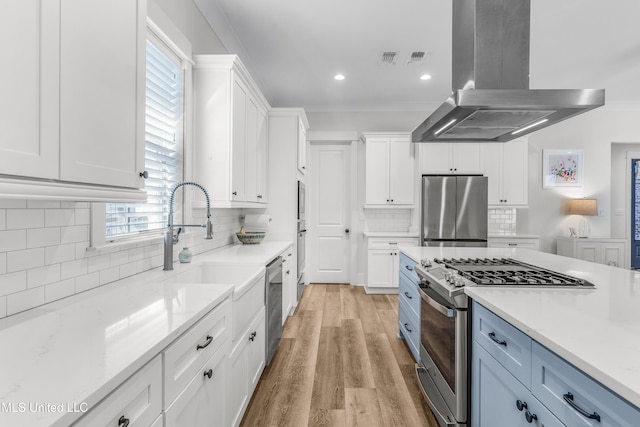 kitchen with white cabinetry, island range hood, stainless steel appliances, and light stone counters