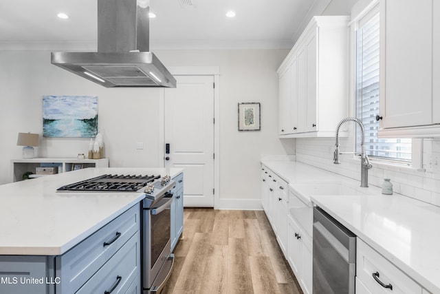 kitchen featuring white cabinetry, island range hood, stainless steel appliances, and ornamental molding