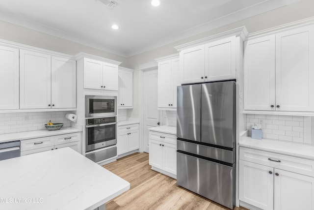 kitchen with appliances with stainless steel finishes, backsplash, white cabinetry, and crown molding